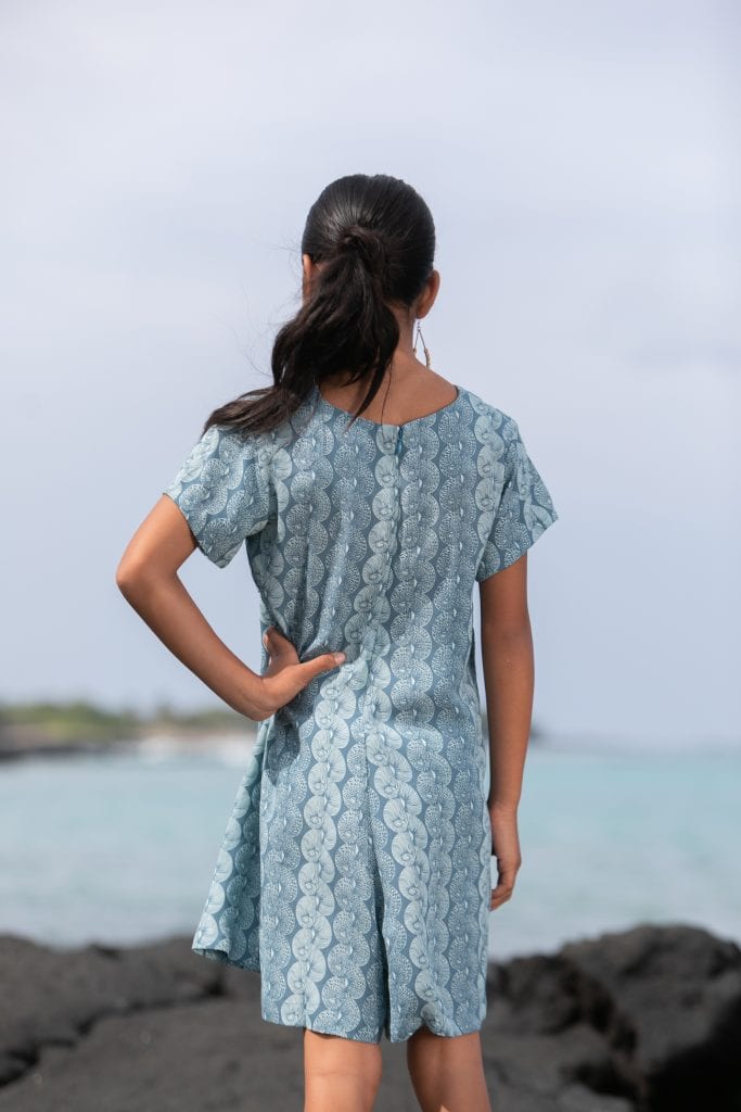 Girl model wearing Opio Romper in a Lei Kupee Print and Real Teal/Blue Tint Color - Back View